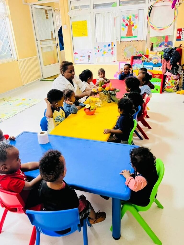 Toddlers seated at tables with a carer during a group activity